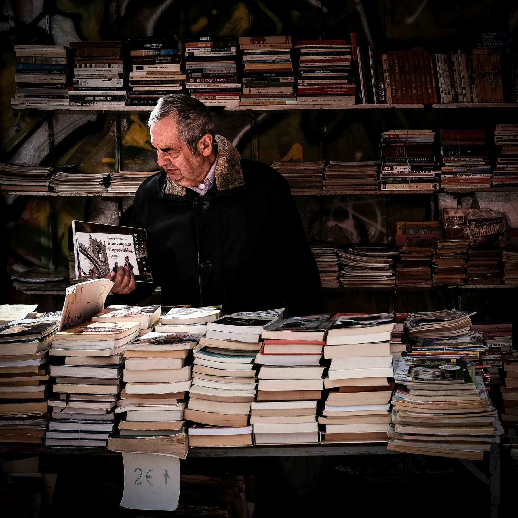 Person examining a book among shelves in a used bookstore