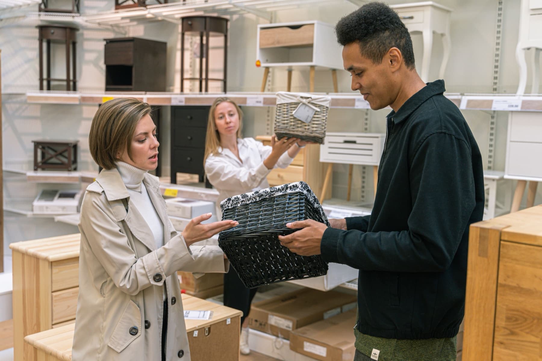 Store associate helping adult shoppers compare woven baskets