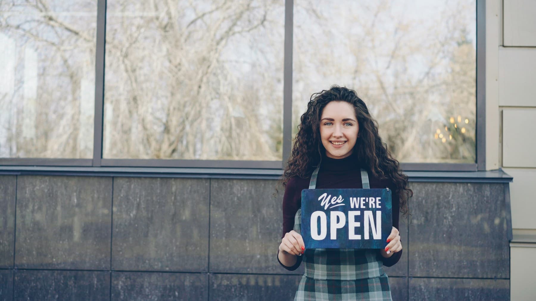 Store operator holding an open sign at a specialty-retail storefront