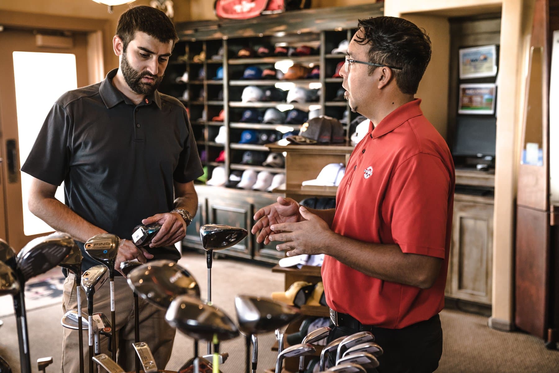 Store associate helping a customer compare golf clubs in a sporting-goods store