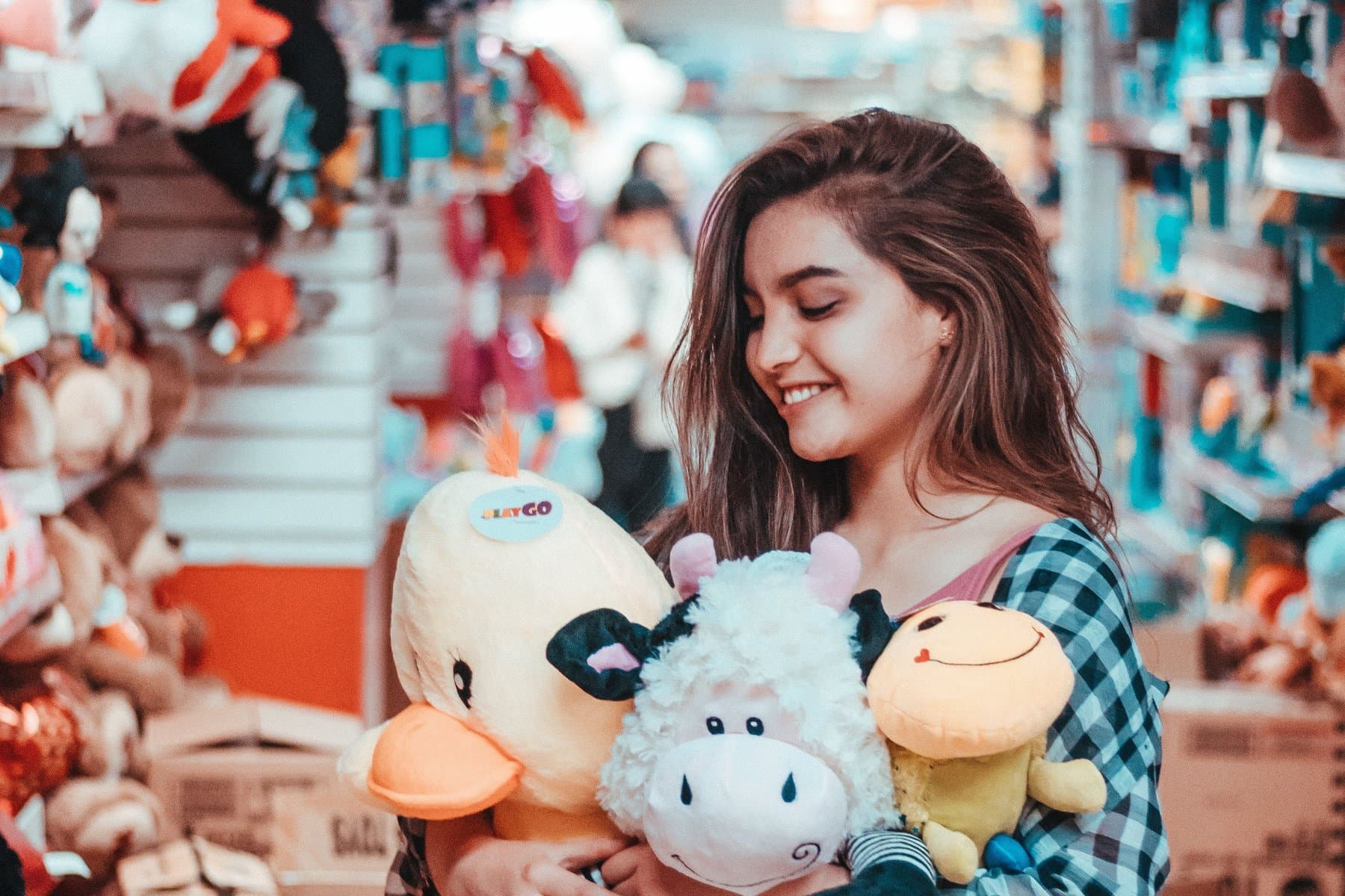 Shopper holding three plush toys in a toy-store aisle